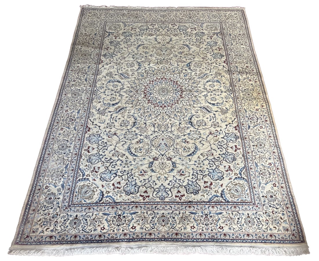 20TH - CENTURY PERSIAN ISFAHAN CARPET: The ivory field centred by a circular medallion, surrounded by dense scrolling vines, palmettes, and floral sprays in soft blues and muted tones, within a broad floral border with guard stripes. CARPE