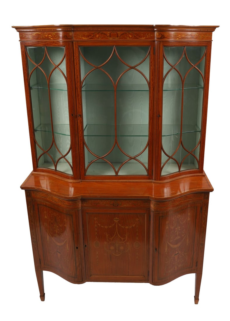 SATINWOOD AND MARQUETRY DISPLAY CABINET: LATE VICTORIAN, Of serpentine form, the glazed upper section with astragal doors above an inlaid base decorated with swags and classical ornament, raised on tapering legs. FURNITURE