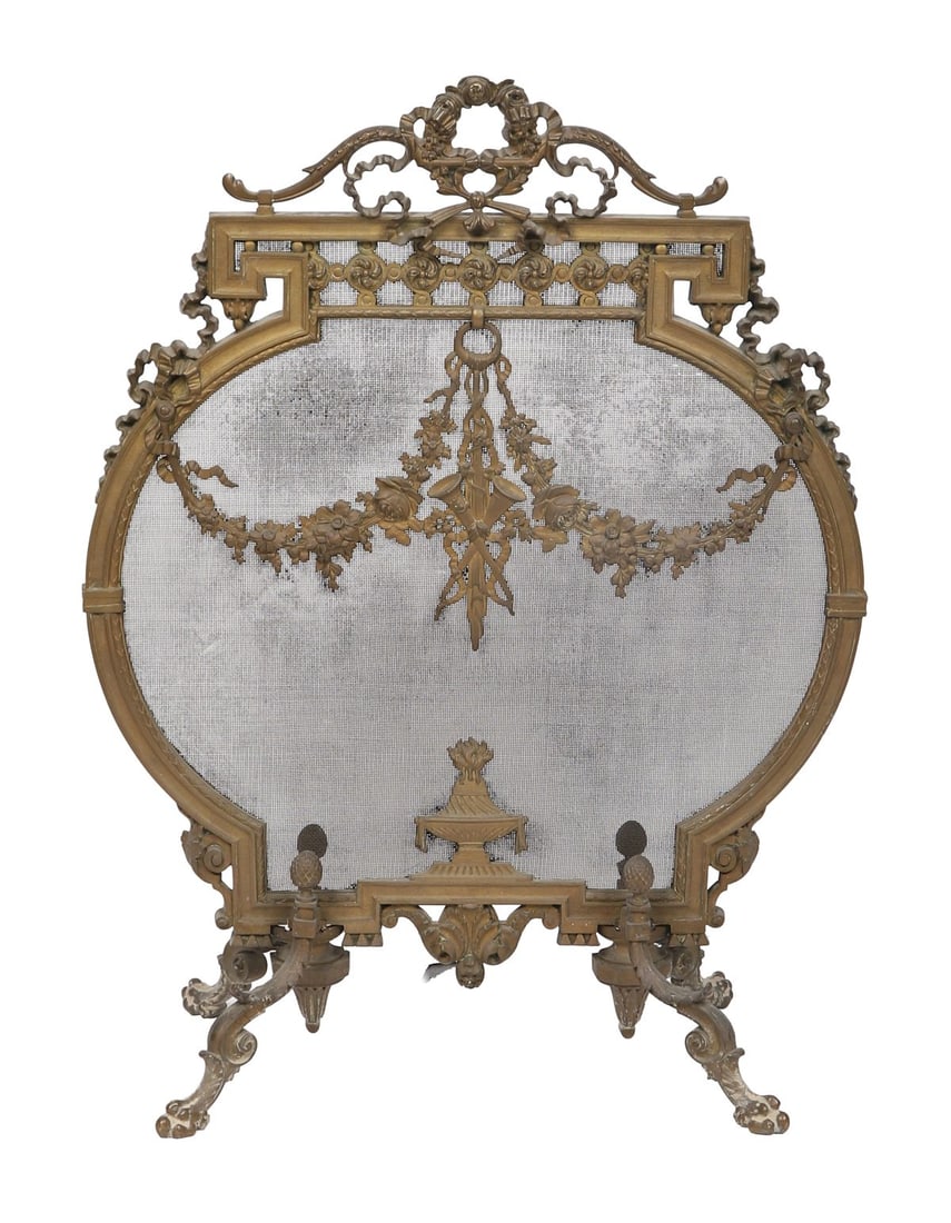 19TH-CENTURY ORMOLU ARMORIAL-SHAPED FIRE SCREEN: An ormolu-mounted fire screen of shaped outline, the frame cast with scrolling foliate ornament and surmounted by a cresting, centred by an armorial-style motif, raised on scrolling supports. FIRE