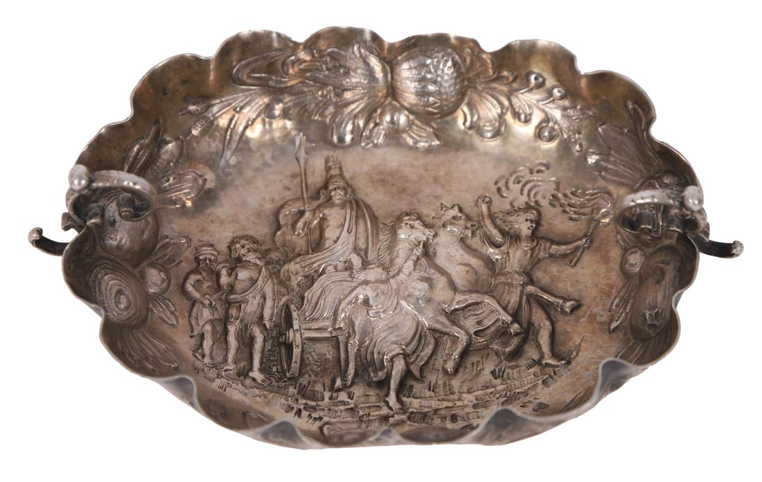 SILVER DISH WITH REPOUSSÉ FIGURAL SCENE: Of shaped oval form, the centre worked in relief with a mounted figure accompanied by attendants, animals and scrolling foliage, within a richly decorated border of shells and rocaille ornament.