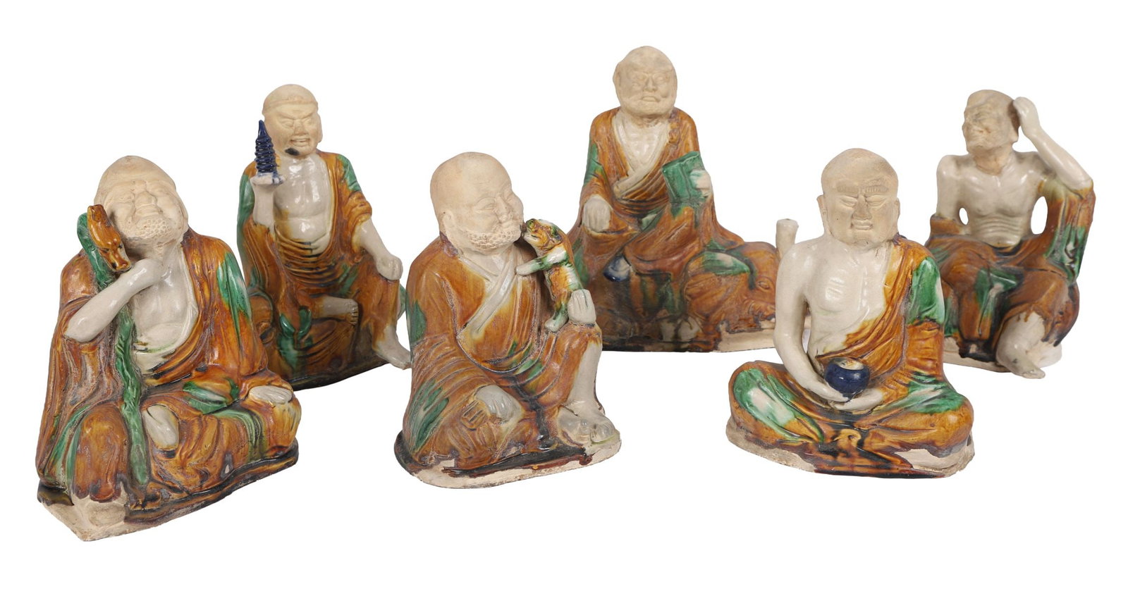 CHINESE STONEWARE FIGURES (SET OF SIX): LATE 19TH / EARLY 20TH - CENTURY, Each modelled as a seated luohan or immortal, decorated in sancai-type glazes of ochre, green and cream, in varying poses. CHINESE