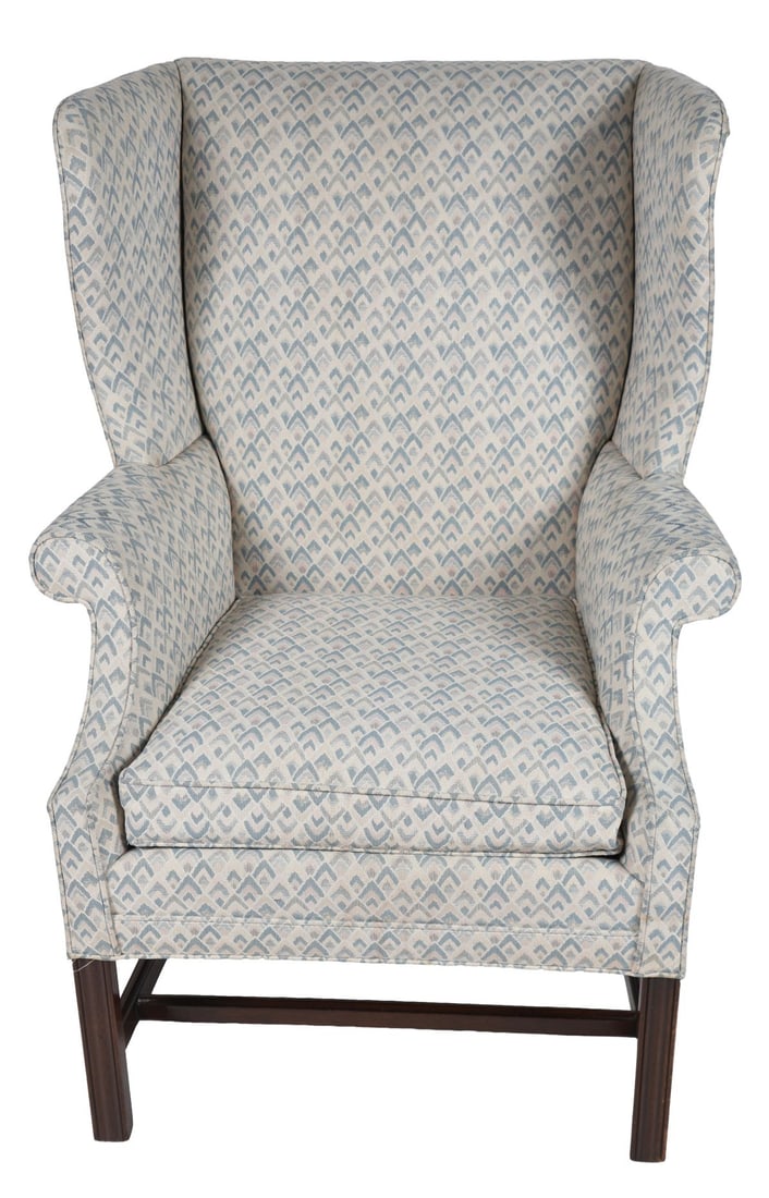 GEORGIAN MAHOGANY & UPHOLSTERED WINGBACK ARMCHAIR: The high back with shaped wings and out scrolled arms, upholstered in patterned fabric, raised on square-section legs united by stretchers. FURNITURE
