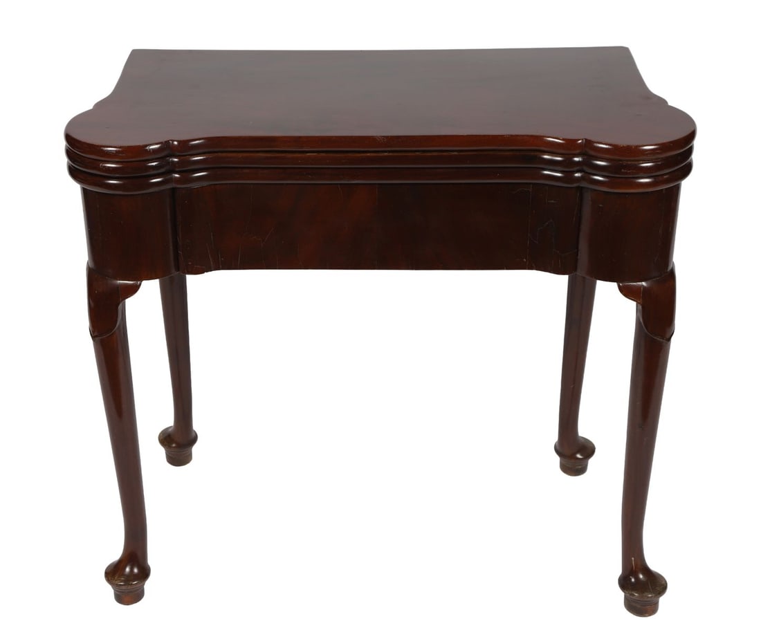 GEORGE II MAHOGANY COMBINATION GAMES TABLE: The fold-over top opening to a baize-lined interior, above a shaped frieze, raised on cabriole legs terminating in pad feet. FURNITURE