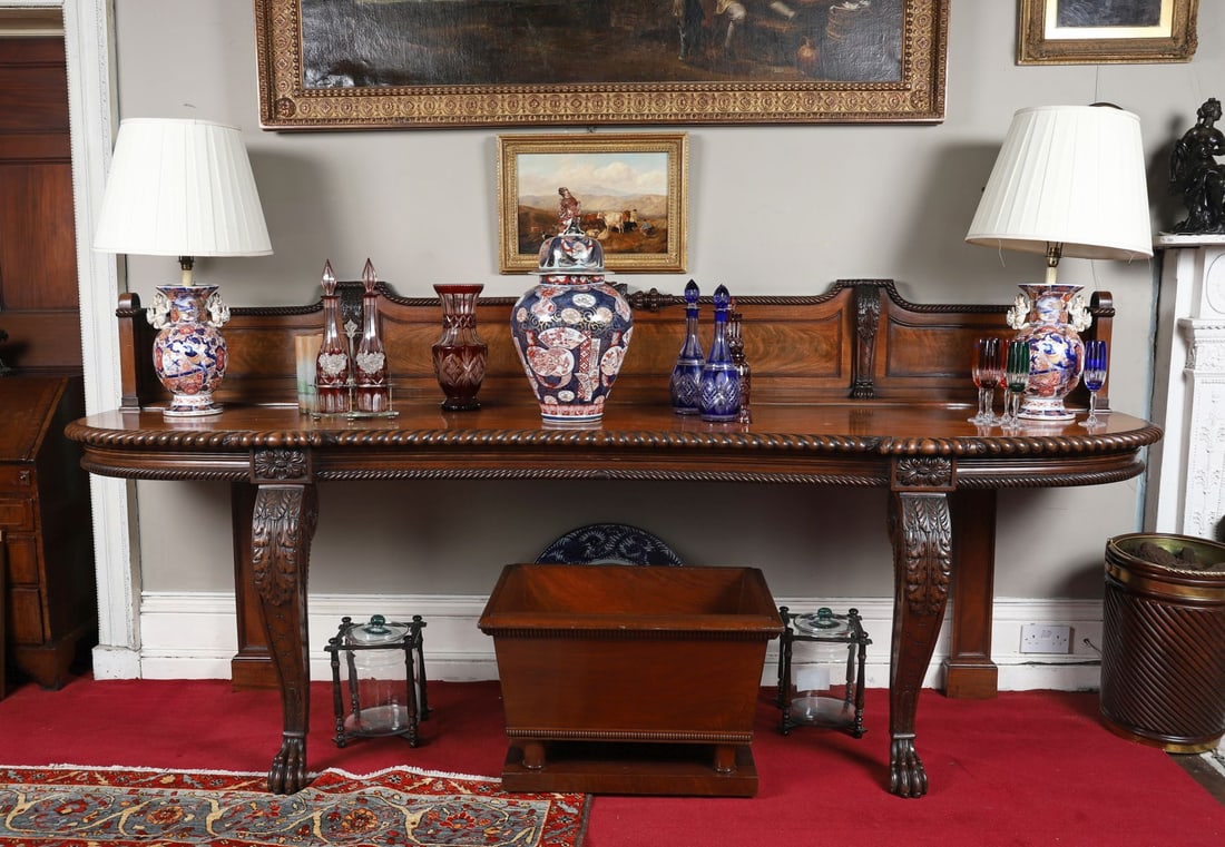 REGENCY IRISH MAHOGANY SHAPED SERVING TABLE: ATTRIBUTED TO WILLIAMS & GIBTON, DUBLINThe serpentine-fronted top with finely figured mahogany and a gadrooned edge, above a shaped frieze centred by a carved floral roundel, raised on bold scrolling 