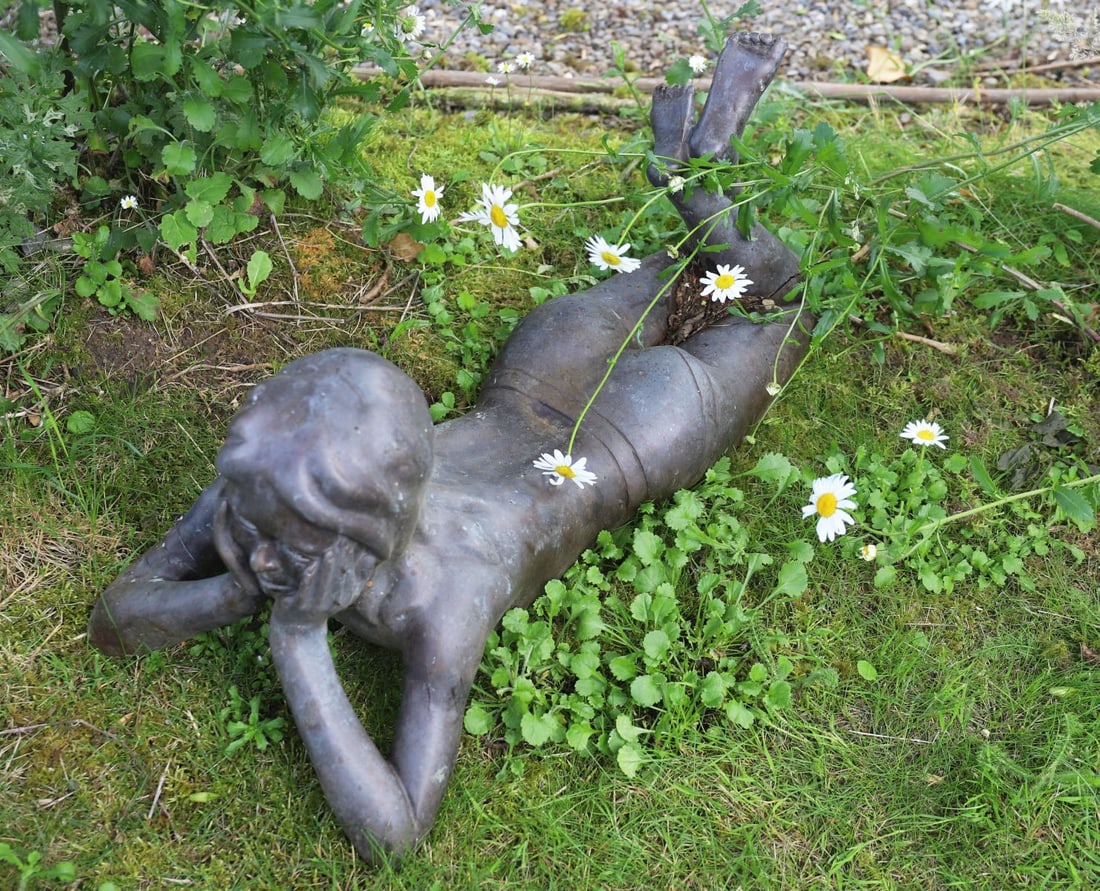 CONTEMPORARY BRONZE GARDEN SCULPTURE: Contemporary bronze sculpture depicting a reclining child resting upon one elbow.