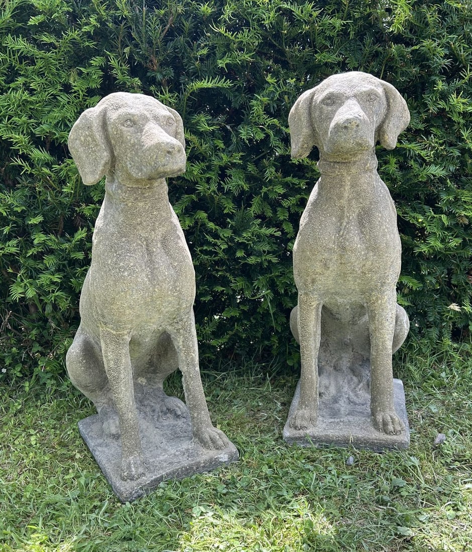 PAIR OF COMPOSITE STONE HUNTING DOGS: Pair of seated composite stone hunting dogs, each modelled in alert pose upon rectangular integral plinths with weathered surface patination.
