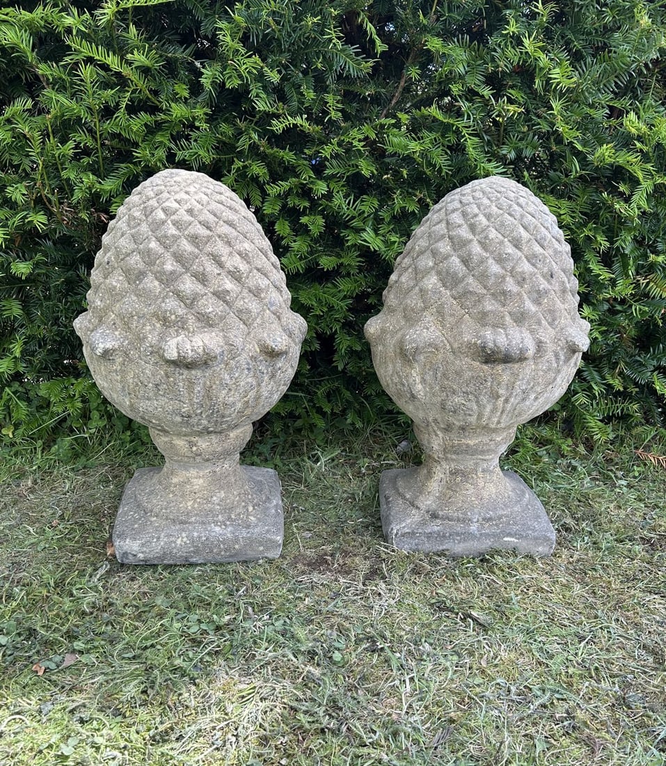 PAIR OF COMPOSITE STONE PINEAPPLE FINIALS: Pair of composite stone pineapple finials, each raised on a circular socle and square plinth base.