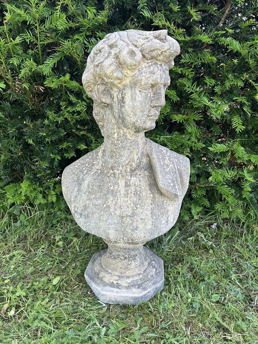 CLASSICAL COMPOSITE STONE BUST OF APOLLO: Weathered composite stone bust modelled as the classical god Apollo, with flowing hair and idealised features, raised on an integral socle and octagonal plinth base. Nicely weathered surface patinatio