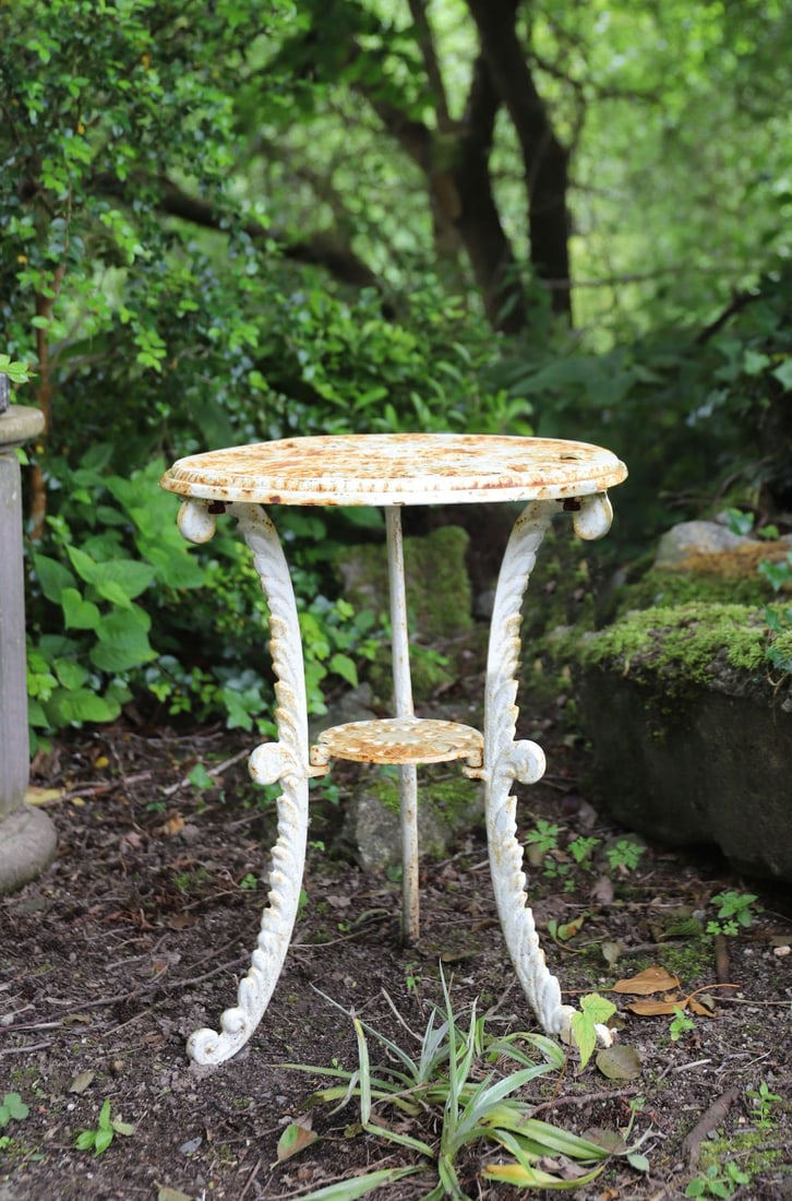 CAST IRON OCCASIONAL TABLE: Small cast iron garden table with circular top raised on three scrolling supports united by a circular undertier.