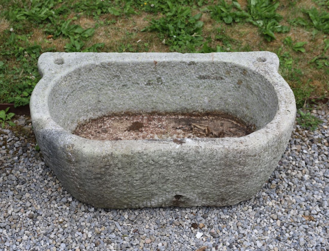 19TH-CENTURY GRANITE STONE TROUGH: Large carved granite trough of rectangular form with rounded ends and integral lug handles, the deep hollowed interior with weathered surface and natural patination throughout.