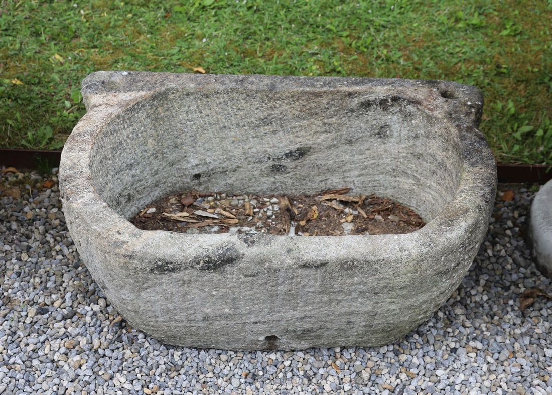 19TH-CENTURY GRANITE STONE TROUGH: Large carved granite trough of rectangular form with rounded ends and integral lug handles, the deep hollowed interior with weathered surface and natural patination throughout.