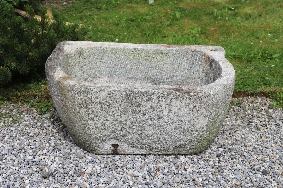 19TH-CENTURY GRANITE STONE TROUGH: Large carved granite trough of elongated rectangular form with rounded ends and integral lug handles, the deep hollowed interior displaying weathered surface and natural patination throughout.