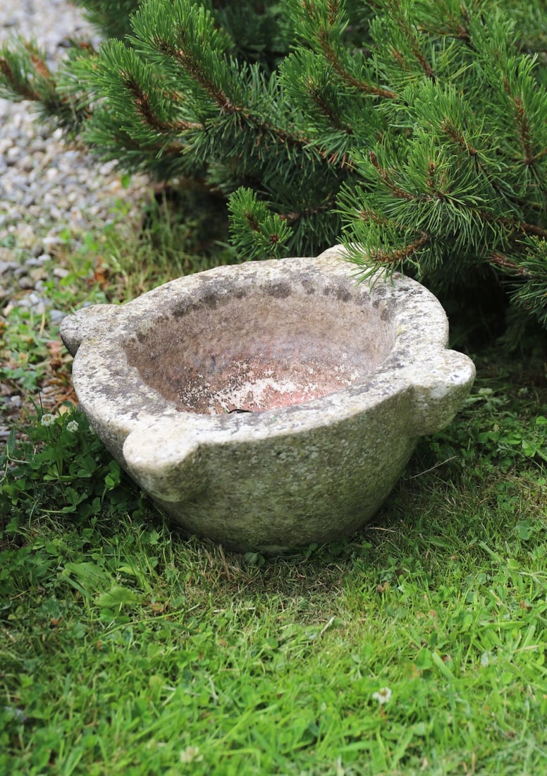 19TH-CENTURY STONE MORTAR: Carved stone mortar of circular form with four projecting lug handles and deep bowl interior, displaying extensive weathering and surface patination.