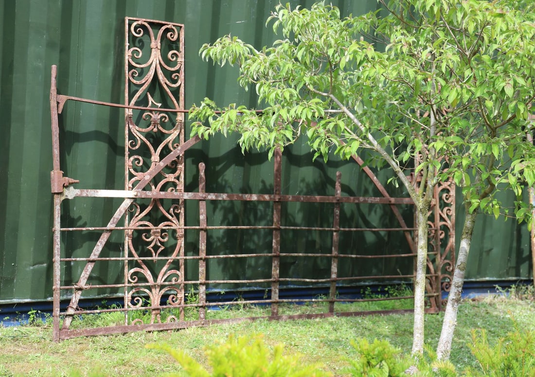 19TH-CENTURY FORGED IRON FARM GATE: A traditional 19th-century iron farm gate, hand-forged with horizontal rails and upright supports. Rusted patina.