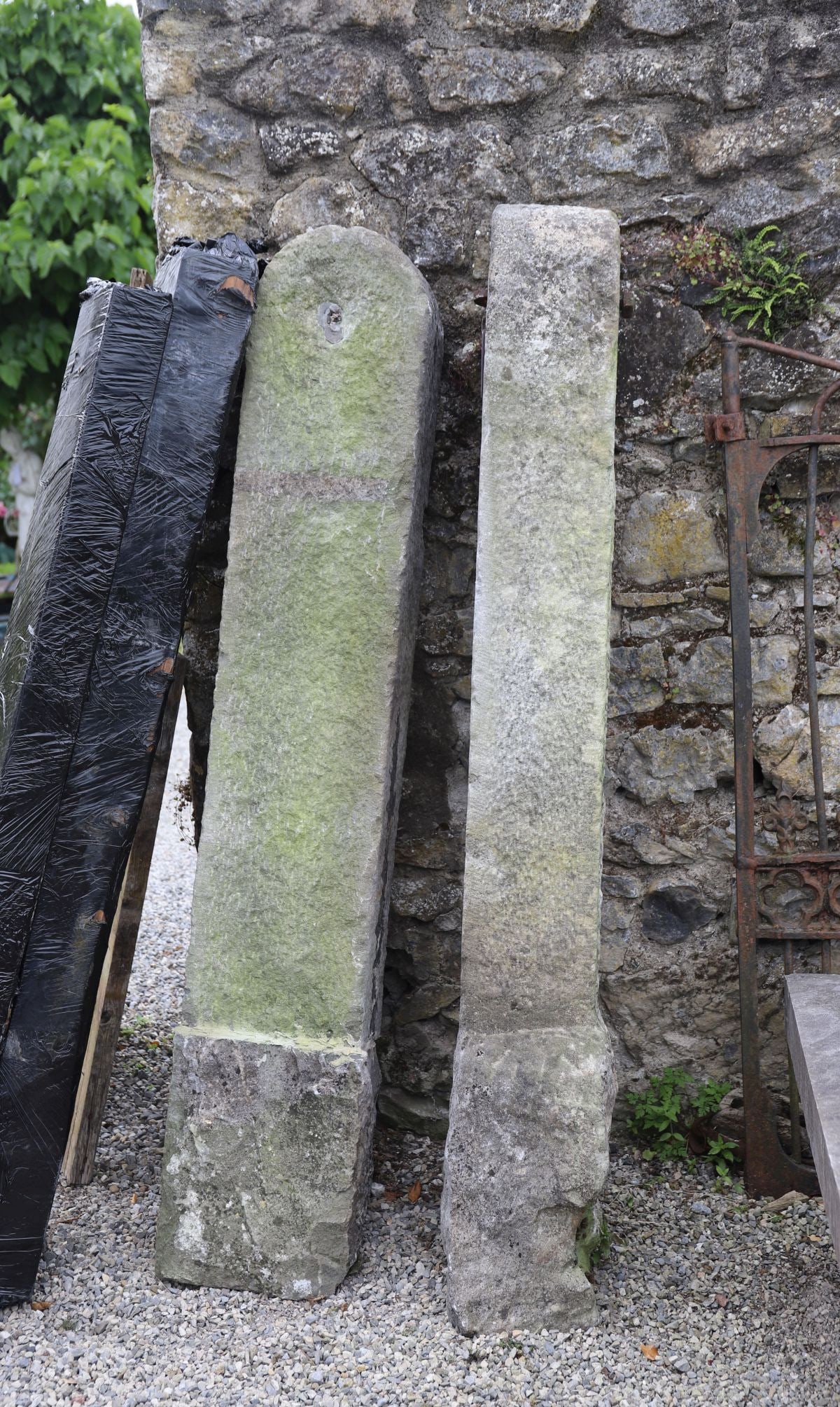 PAIR OF 19TH-CENTURY LIMESTONE GATE POSTS: Pair of substantial 19th-century limestone gate posts of tapering rectangular form with chamfered shoulders and original iron fittings.