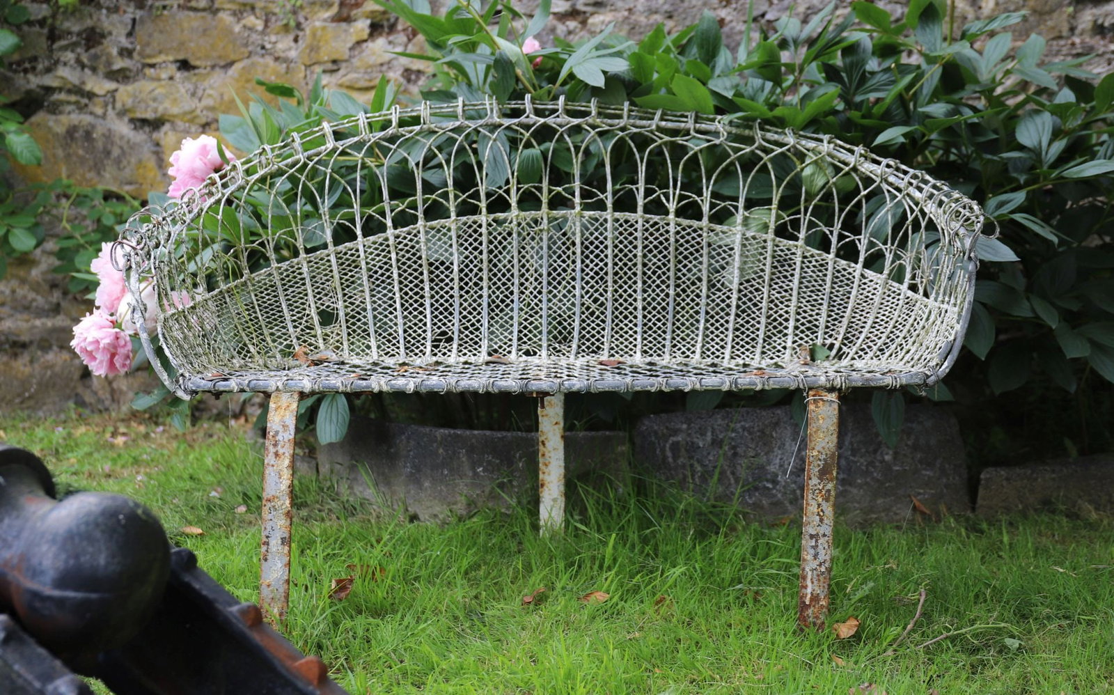 LATE 19TH-CENTURY WIREWORK GARDEN BENCH: Decorative wirework garden bench with shaped back, scrollwork detailing and mesh seat, retaining traces of original painted finish.