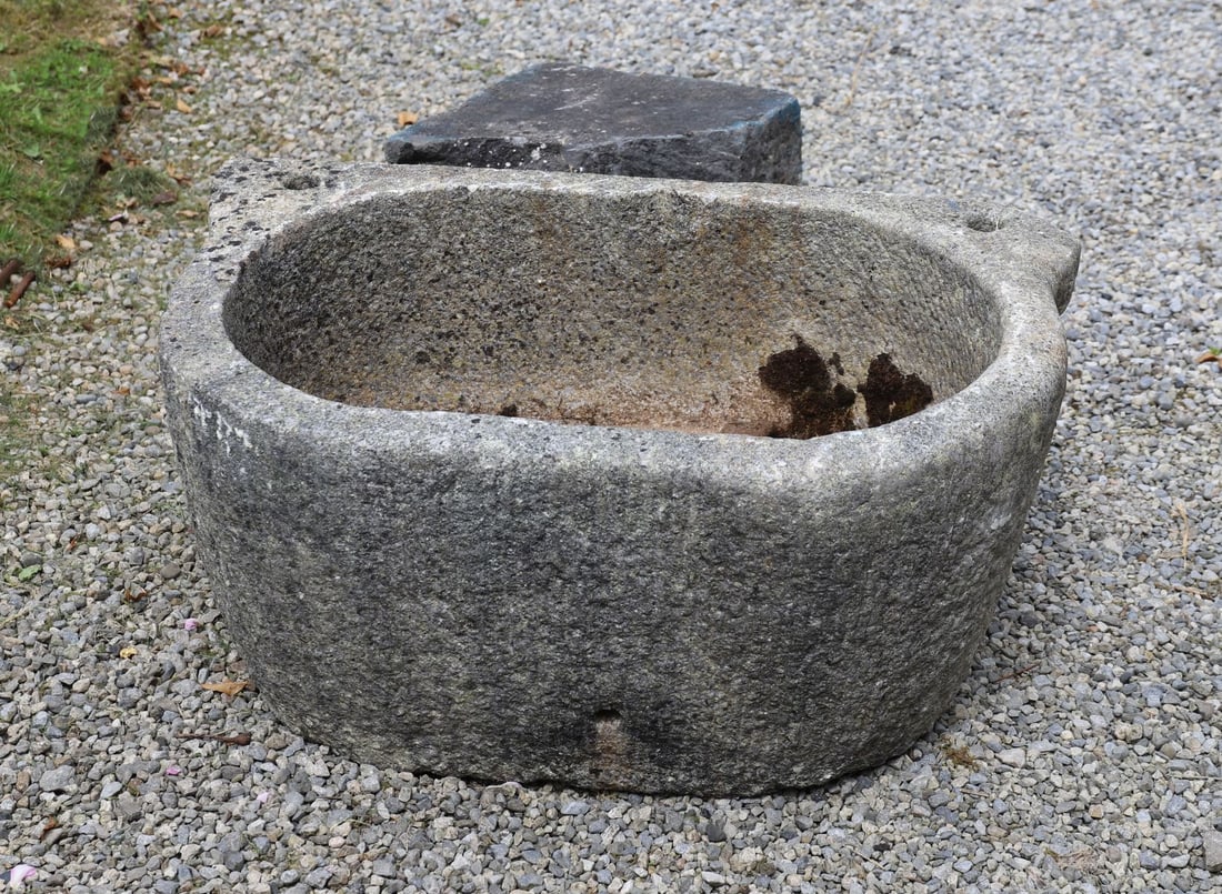 19TH-CENTURY GRANITE STONE TROUGH: Substantial hand-carved granite trough of rounded rectangular form with integral lug handle and weathered surface.