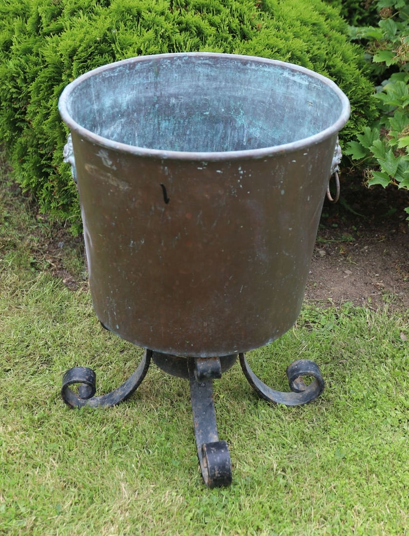 19TH-CENTURY COPPER JARDINIERE ON CAST IRON STAND: Large 19th-century copper jarndiniere of tapering circular form with rolled rim and lion mask ring handles, raised on a cast iron stand with scroll feet. Attractive verdigris patination throughout.