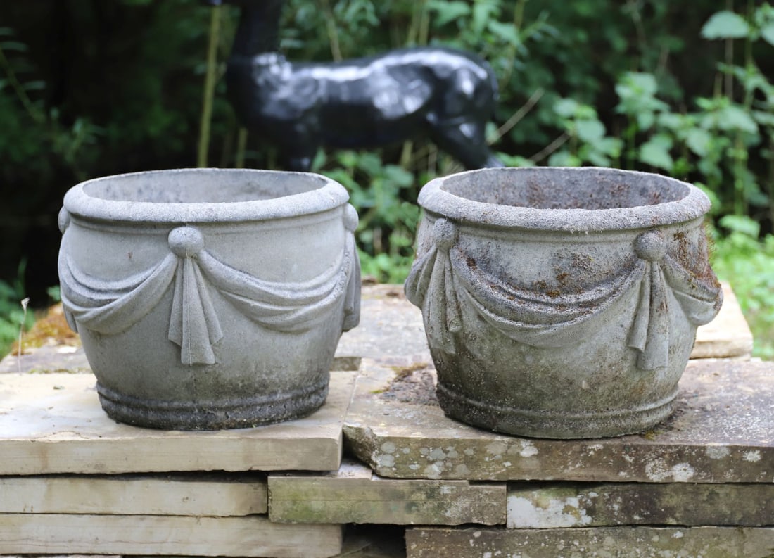 PAIR OF COMPOSITE STONE JARDINI?RES: The circular bodies decorated with swag and ribbon ornament, raised on integral circular bases.