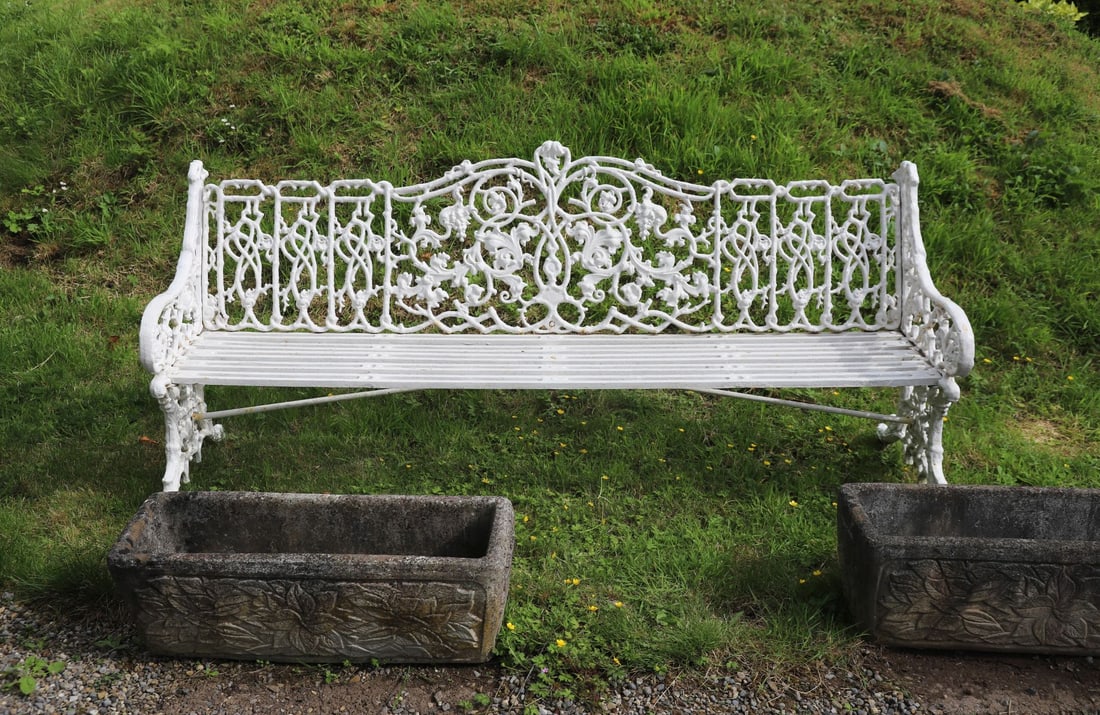 LARGE & HEAVY CAST IRON GARDEN BENCH: CLASSICAL FOLIATE DESIGN a white-painted cast iron garden bench with a highly ornate backrest featuring foliate scrollwork and roundels. Shaped arms and pierced seat with flowing decoration.