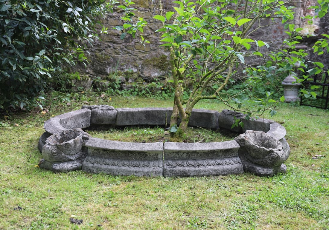MOULDED STONE POOL SURROUND: Moulded stone pool surround formed from sectional elements with bold scallop shell decoration and weathered surface patination. Suitable as a formal garden focal point.