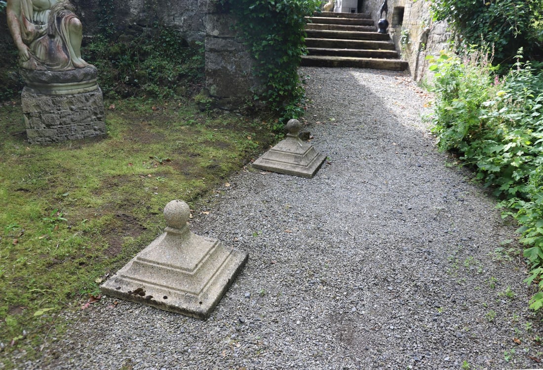 PAIR OF MOULDED GRANITE PIER CAPS: each of square form below a turned finial.