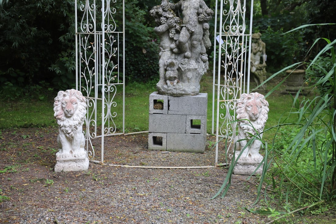 PAIR OF MOULDED STONE FIGURES OF SEATED LIONS: A pair of moulded stone lions in seated pose, each with detailed mane and paw positioning. Classical garden guardians with aged finish.