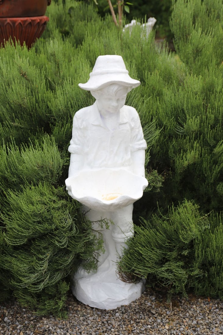CAST IRON FIGURAL BIRDBATH: Cast iron garden figure of a young boy in broad-brimmed hat holding a shell-form basin, raised on an integral naturalistic base.