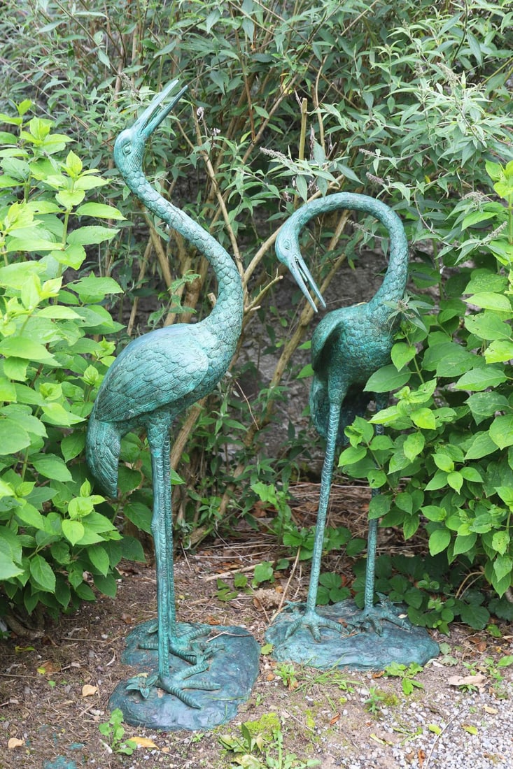 PAIR OF BRONZE-PATINATED HERON GARDEN SCULPTURES: Decorative pair of herons with verdigris patination, standing upon naturalistic bases.