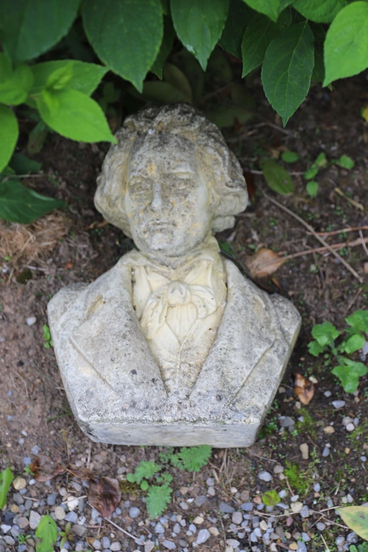 COMPOSITE STONE BUST - BEETHOVEN: A composite stone bust traditionally believed to represent Beethoven, modelled with flowing hair and cravat, in classical dress. Cast with smooth detail and a weathered finish.
