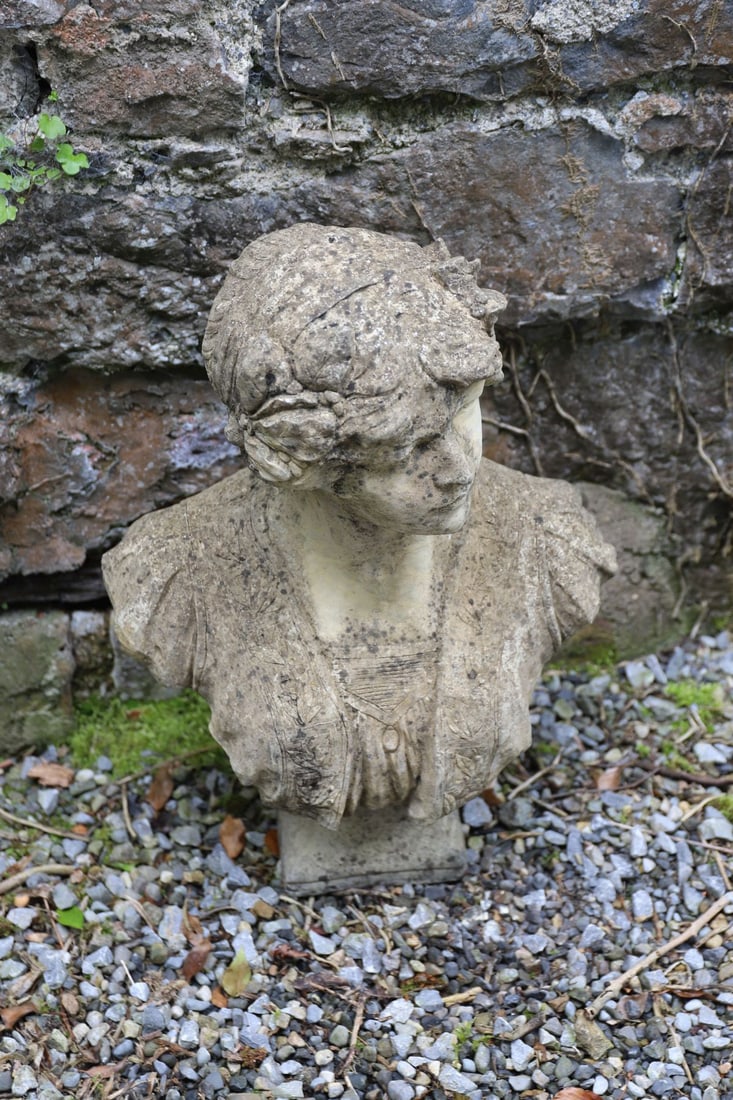 COMPOSITE STONE CLASSICAL FEMALE BUST: Composite stone bust of a classical maiden with draped costume and floral headdress. Weathered patination.
