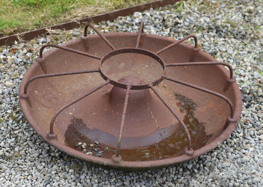 CAST IRON PIG TROUGH: The circular cast iron trough with radial division framework and central hub, cast with maker?s inscription to the rim. A substantial agricultural piece with attractive weathered patination.