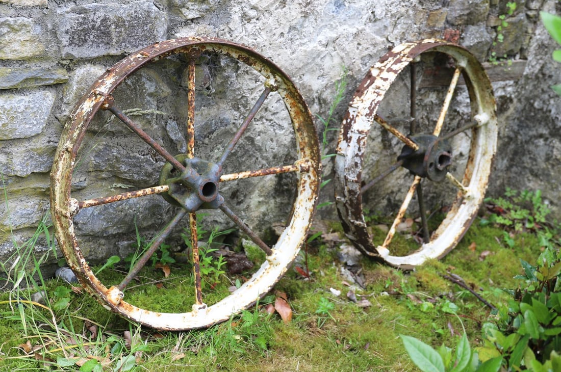 PAIR OF CAST IRON CART WHEELS: The matching wheels with iron hubs and spokes, retaining traces of original paint and surface patination.