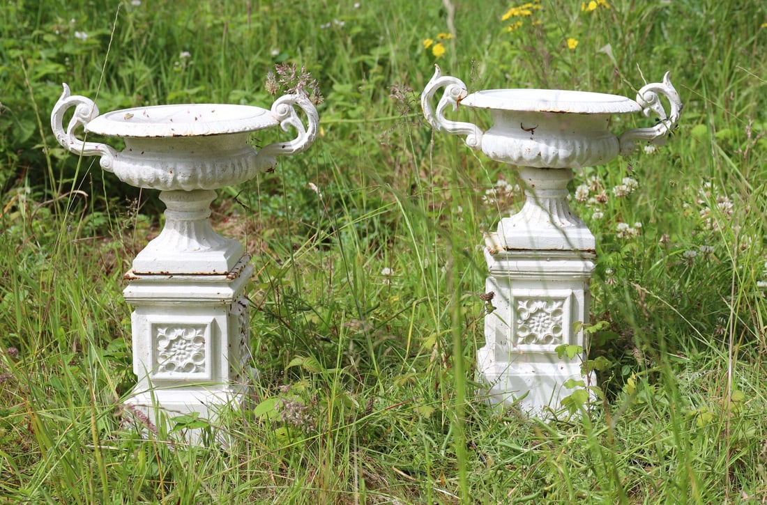 PAIR CAST IRON CAMPANA URNS: each with scroll handles, raised on a rose panelled square moulded base.