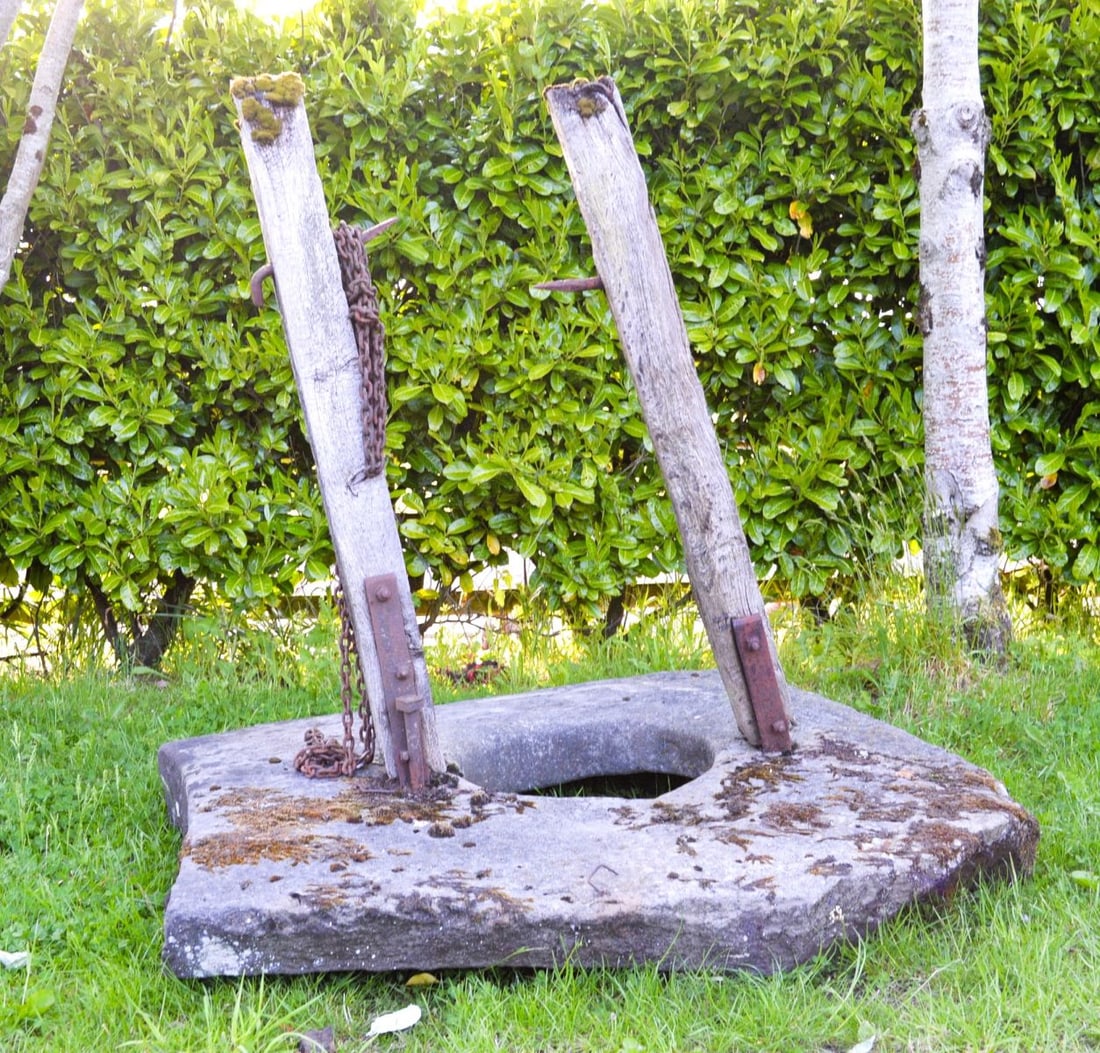 18TH-CENTURY STONE WELL HEAD: WITH ORIGINAL IRON AND TIMBER MOUNTS An 18th-century stone well head, circular in form, complete with original wrought iron over-arch and timber winding mechanism. Rare surviving example with authenti