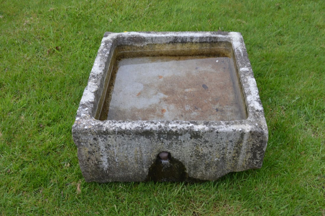 19TH-CENTURY CUT LIMESTONE TROUGH PLANTER: A rectangular 19th-century trough carved from solid limestone, later adapted for use as a garden planter. Weathered surface with tool marks visible.
