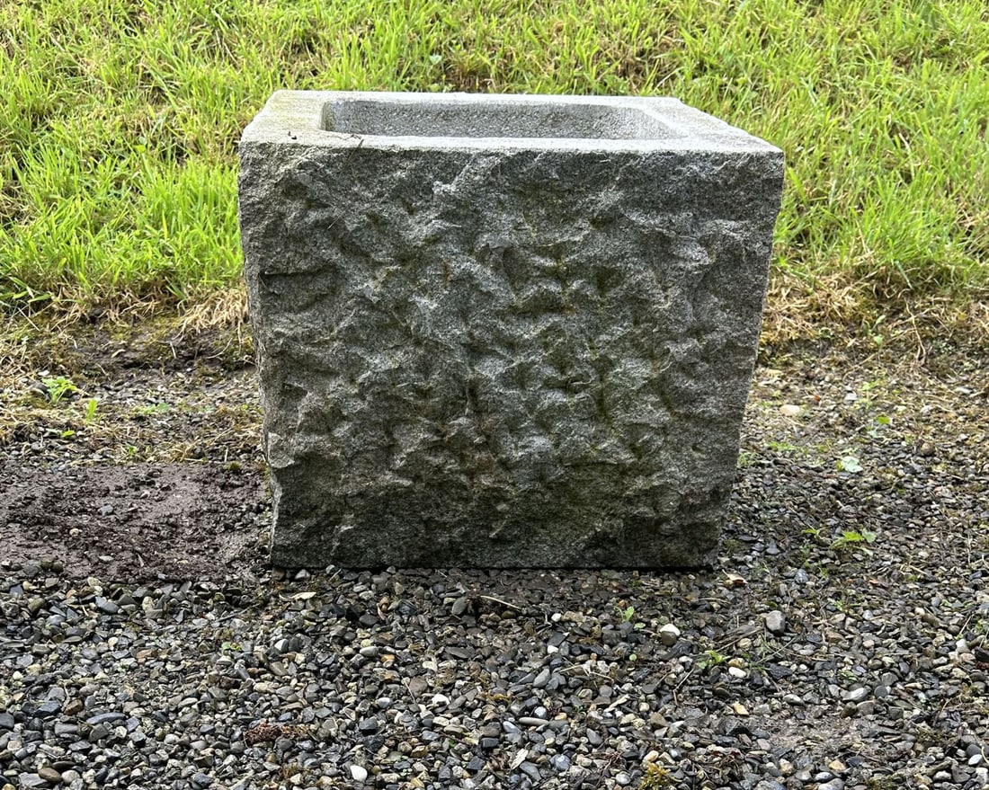 PAIR OF STONE TROUGH PLANTERS: The square planters with rough-hewn exterior surfaces and recessed interiors, carved from solid stone