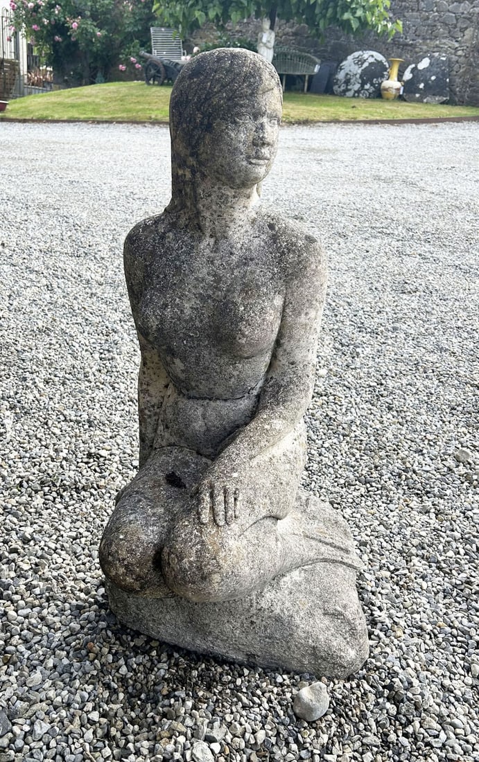 CONTEMPORARY STONE FIGURE: Contemporary carved stone figure of a seated female with folded legs and stylised head covering, weathered throughout.