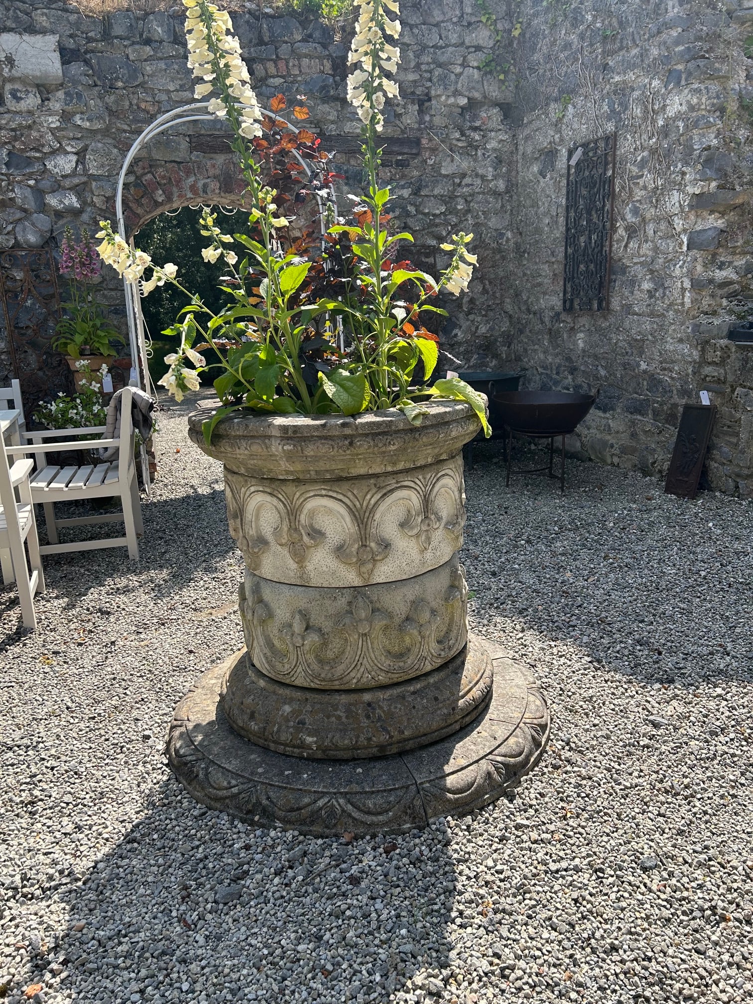 ORNATE MOULDED STONE WELL HEAD: of cylindrical form with leaf decoration mounted on a stepped base.90 cm. high; 80 cm. diameter