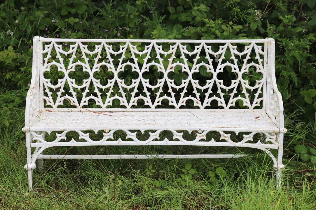 CAST IRON GOTHIC GARDEN BENCH: with tracery back and seat, raised on scroll ends.