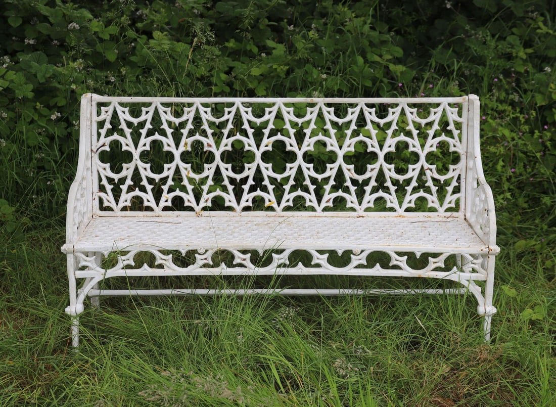 CAST IRON GOTHIC GARDEN BENCH: with tracery back and seat, raised on scroll ends.