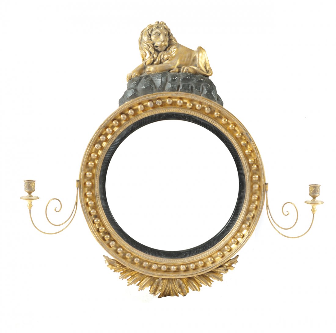 Important Regency carved giltwood framed convex mirror,: the circular plate within a bobbin beaded and moulded frame, surmounted by a reclining lion with sconces to the fore, over a leaf carved base Worldwide shipping available: shipping@sheppards.ie 120 cm