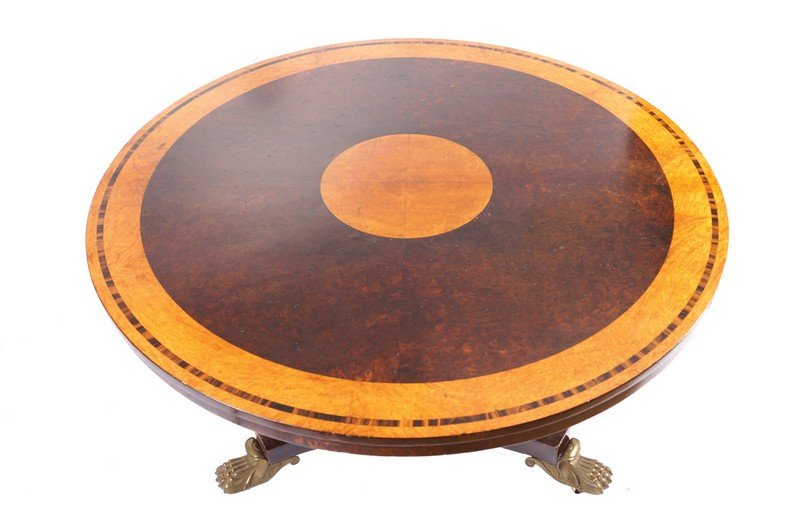 Important Regency period amboyna, coromandel, and: the circular cross banded and inlaid top above a conforming frieze raised on a chamfered cavetto stem and platform, terminating on brass paw feet Dimensions: 120 cm. deep; 68 cm. high