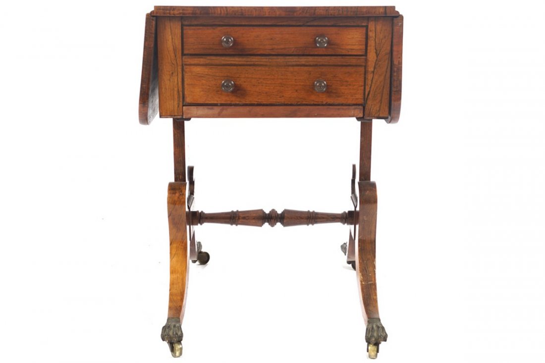 SMALL REGENCY PERIOD ROSEWOOD SOFA TABLE: SMALL REGENCY PERIOD ROSEWOOD SOFA TABLE the rectangular top with drop leaves above a real and opposing faux drawer raised on pillar and sabre ends terminating on brass feet and casters 60 cm. high; 3