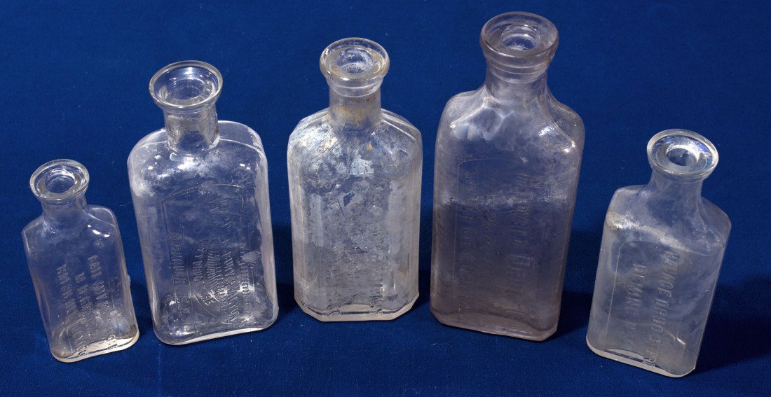 New Mexico Drug Store Bottle Collection: NM - c1894 - Lot of 5. 1) Howell Drug Company / The Service Store / Silver City, New Mex. 4 ounce clear, slightly purple, medium stain in and out. 5.5" tall. No glass maker on bottom. C1910