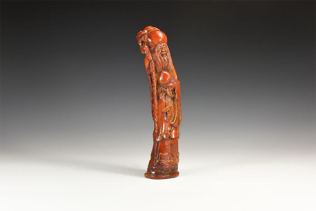 Chinese Shou-Xing Figure: An undated archaistic moulded figure of Shou-Xing, Taoist god of long life, with large bulbous head, smiling face and long beard; long lose robes falling to feet, holding a peach in left hand and drag