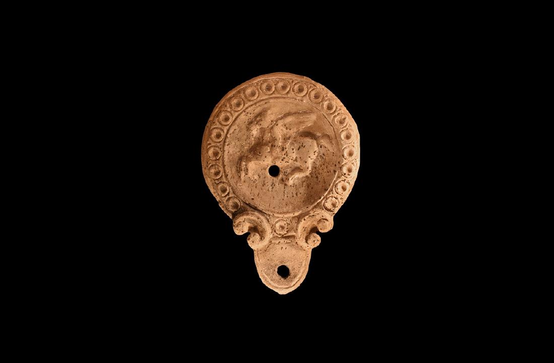 Roman Oil Lamp with Flying Pegasus: An dated archaist ceramic buff coloured oil lamp in 1st-2nd century AD style, with rounded nozzle and pelta shaped volutes to the side; deep body with flat rim decorated with series of ring and dot mo