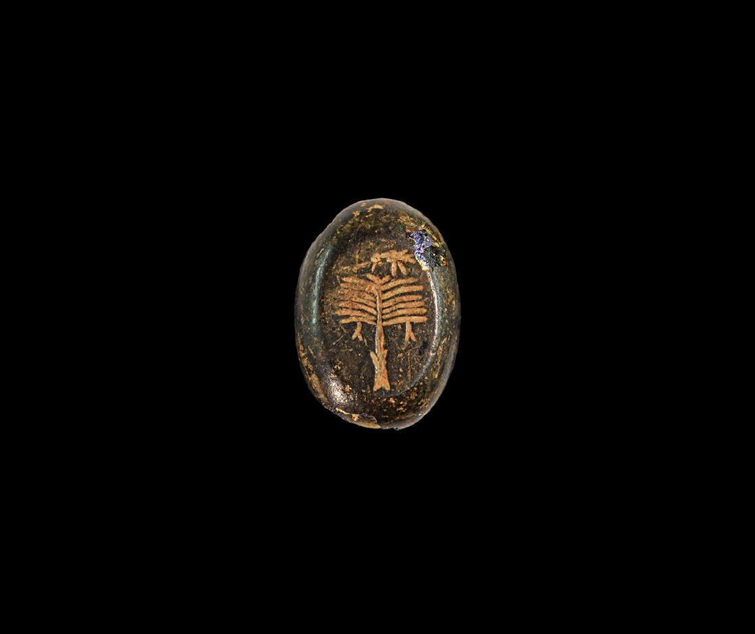 Punic Intaglio with Palm Tree and Bird: 3rd-2nd century BC. A brown glass intaglio engraved to the top with a palm tree with fruit hanging down and bird perched at the top. 4.24 grams, 23mm (1"). Property of a London gentleman; acquired by 