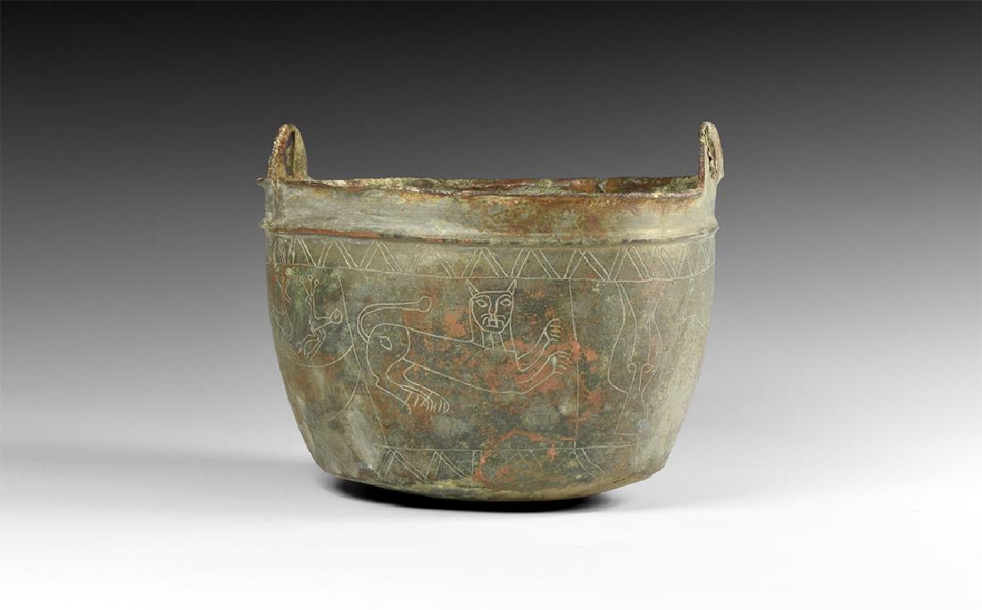 Cauldron with Lion, Birds, Gryphon and Wolves: 1st millennium BC. A small bronze cauldron with domed underside, repoussÃ© flange below the rim, two lateral D-shaped pierced suspension lobes; incised frieze comprising a pair of opposed birds, a p