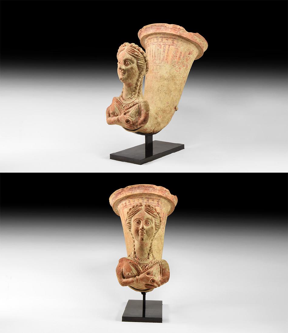 Parthian Goddess Anahita Rhyton: 3rd century BC-2nd century AD. A terracotta rhyton with flanged and stepped rim, tapering curved body, figural finial of the goddess Anahita with diadem; bands of red and cream geometric detail to the